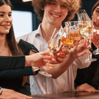 Sitting by the bar table. Group of people in beautiful elegant clothes are celebrating New Year indoors together.