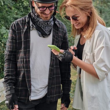 Middle age couple in helmet using mobile phone outdoors, travel together.